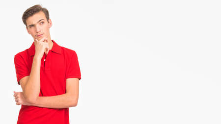 Portrait of thoughtful young man looking up isolated over white background. Photo of  pensive white guy in a red shirt.  Male person is thinking. Person is thinking looking away.の写真素材