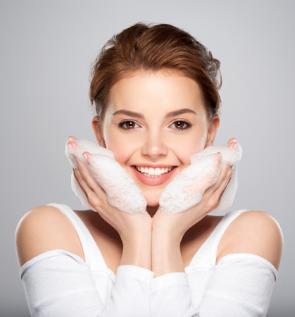 Beautiful face of young caucasian woman with perfect healthy skin, isolated.   Pretty white smiling  model caring of face. Beauty treatment concept. Skin care concept.の写真素材