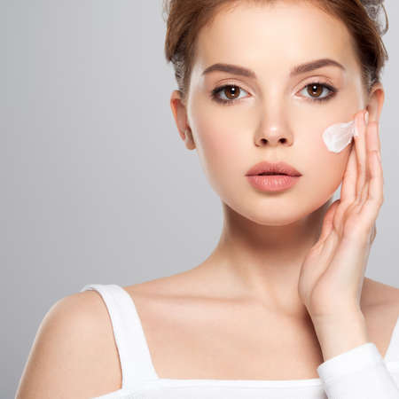Spot of cosmetic cream on a woman's face. Beautiful face of young caucasian woman with perfect healthy skin, isolated.   Pretty white model caring of face.  Woman applying cream on face.の写真素材
