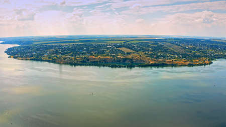 Aerial view over beautiful suburb with a wide river with privat houses. Top view over a people settlement near water.の写真素材