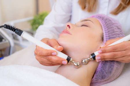 Woman in a spa salon on cosmetic procedures for facial care. Cosmetologist making a woman a...