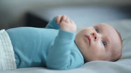 Sweet newborn boy lies on the sofa. Beautiful infant boy with blue eyes.  Cute two-month-old baby in...