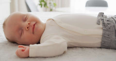 Cute small baby sleeping with a smile on his face. Beautiful infant baby sleeping at home.  Close-up...