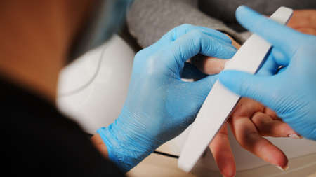 Nail care at home. Process of nail treatment in a nail salon. A view from behind the nail master...
