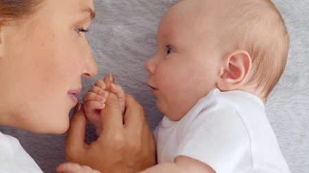 Happy newborn baby with his mother. Healthy newborn baby in a white t-shirt with mom. Closeup Faces...
