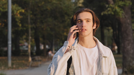 Young man is talking on a cell phone while walking down the street. Positive guy is talking on the...