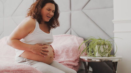 Expectant mother suffering from pregnant pain. Pregnant woman feeling ache lying on a bad.  Pregnant adult woman feels pain  expecting childbirth. Pregnant woman cannot fall asleep from abdominal painの写真素材