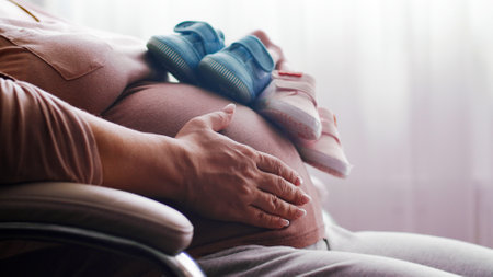Happy pregnant woman expecting  twins. Pregnant woman feeling happy at home while taking care of her child. Pregnant woman resting alone at home strokes touches her big belly, close up.の写真素材