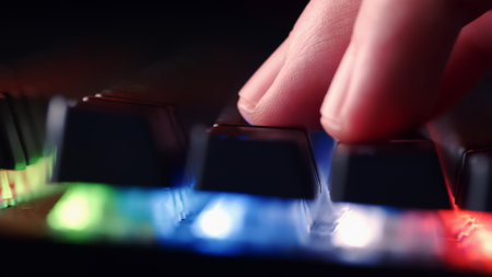 Human hand  is on the keys on the computer keyboard, close up view. Fingers  on the gaming keyboard key with led light, macro shot. Low angle view with a soft focus.の写真素材