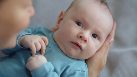 Newborn baby happy to looking on his mom . Happy mother spends time with her child. Mother playing with an infant kid.   Infant with blue eyes happy being with mama. Maternity and childcare concept.の写真素材