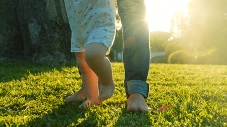 Walking children's bare feet on a green lawn close-up. Child learns to take the first steps on the...
