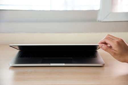 Silver laptop little open with right hand, front angle