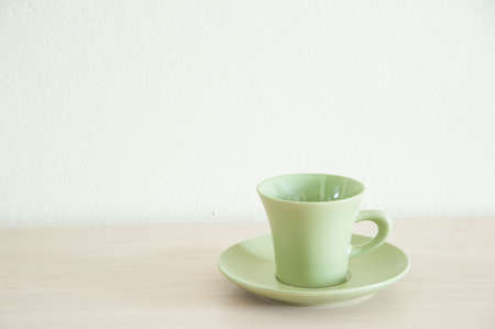 Green coffee cup for take a break on the wooden table. Right space of frame.の写真素材