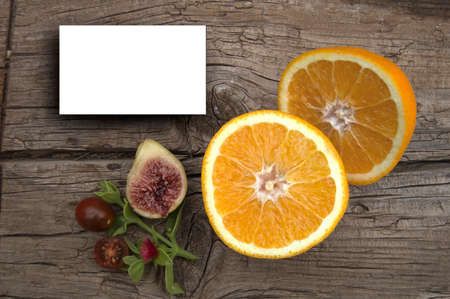 White card for display with oranges and figs on wood