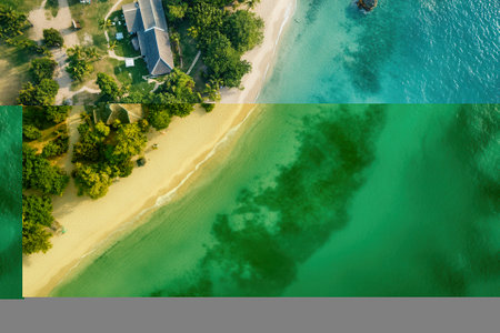 Aerial view of tropical beach, houses, and clear turquoise water.の素材