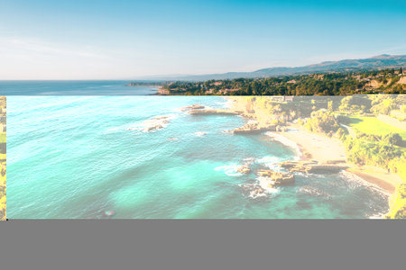 Aerial view of coastal mansion, ocean, beach, and cliffs.の素材