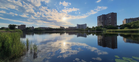 Calm lake reflecting a city skyline under a vibrant skyの素材