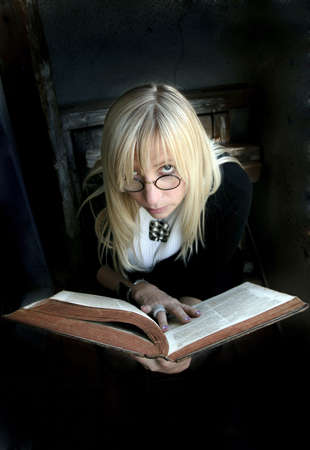 Portrait of the beautiful blonde woman with glasses and old bookの写真素材
