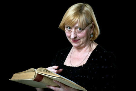 Happy senior woman with book and glasses on blackの写真素材