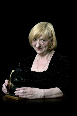 portret of happy senior woman with old  coffee mill on blackの写真素材