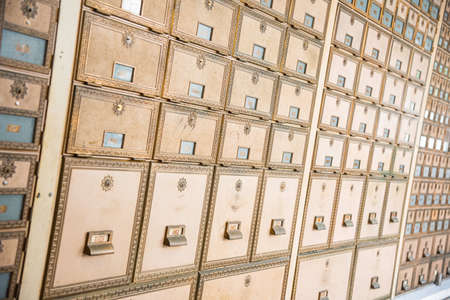 Rows of mid-century modern design post office mailboxes in brass metal.