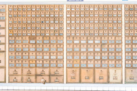 Rows of mid-century modern design post office mailboxes in brass metal.