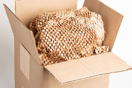 A close-up shot of an open generic brown carton packaging box with brown cross-cut paper filling.の写真素材