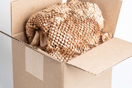 A close-up shot of an open generic brown carton packaging box with brown cross-cut paper filling.の写真素材