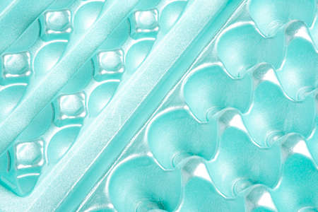 A close-up shot of an empty and used polystyrene egg carton set on a plain neutral background.
