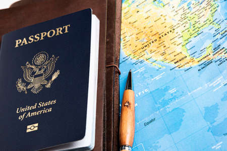 The foil-stamped dark blue front cover of an American passport with leather-covered travel notebooks...