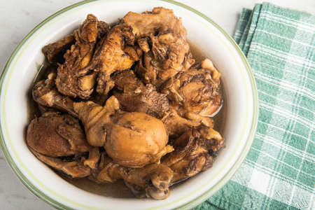 A serving of Filipino-style chicken adobo dish in a bowl with green napkin set on a marble tabletop.の写真素材