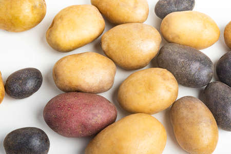 An assorted color raw and fresh potatoes artfully arranged and set on flat white surface table background.の写真素材