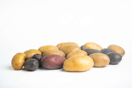 An assorted color raw and fresh potatoes artfully arranged and set on flat white surface table...