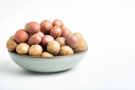 Raw and fresh baby potatoes artfully arranged in a bowl and set on white background.の写真素材