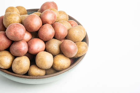 Raw and fresh baby potatoes artfully arranged in a bowl and set on white background.の写真素材
