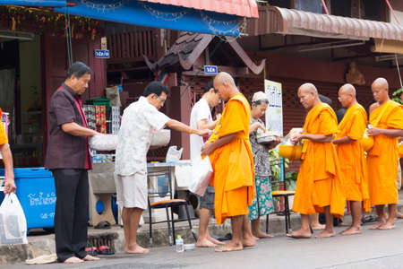SAKONNAKHON , THAILAND - October 30:unidentified people give food offerings to Buddhist monks on October 30, 2012 in Sakonnakhon, Thailand. Thai traditional, people will make merit making by give food to monkのeditorial素材