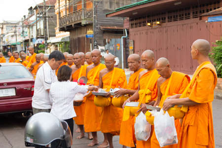 SAKONNAKHON , THAILAND - October 30:unidentified people give food offerings to Buddhist monks on October 30, 2012 in Sakonnakhon, Thailand. Thai traditional, people will make merit making by give food to monkのeditorial素材