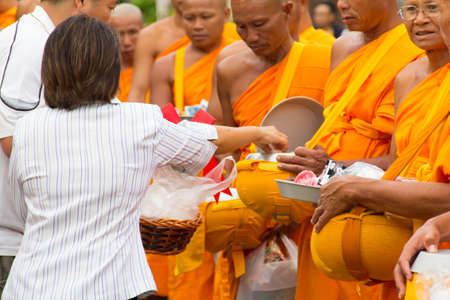 SAKONNAKHON , THAILAND - October 30:unidentified people give food offerings to Buddhist monks on October 30, 2012 in Sakonnakhon, Thailand. Thai traditional, people will make merit making by give food to monkのeditorial素材