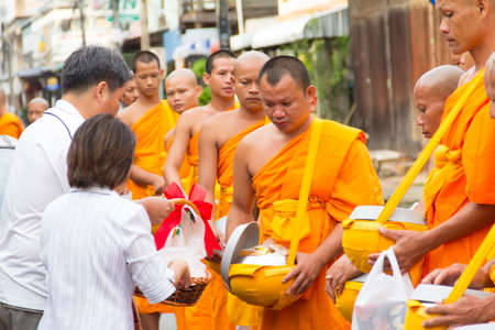 SAKONNAKHON , THAILAND - October 30:unidentified people give food offerings to Buddhist monks on October 30, 2012 in Sakonnakhon, Thailand. Thai traditional, people will make merit making by give food to monkのeditorial素材