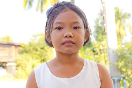 portrait of the girl standing in the shade of a tree on the streetの写真素材