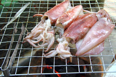 Close up fresh squid barbeque grilled on charcoal stoveの写真素材