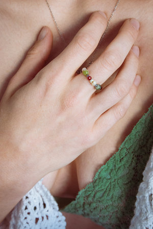 Close up of a woman's hand holding a silver ring with a green gemstoneの写真素材