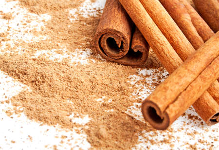 Cinnamon sticks with its dust around it over a white background