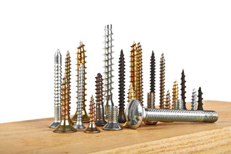 Various screws on wooden plank on a white background