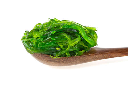 Japanese Cuisine - Chuka Seaweed Salad with sesame seeds in wooden spoon on a white background....