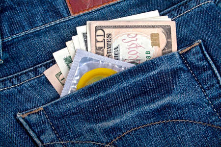 Yellow condom and American dollars in a blue jeans pocketの写真素材
