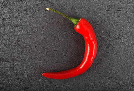 Red chili pepper on black background, top view
