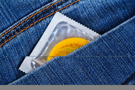 Yellow condom in a blue jeans pocket, concept for safe sex.の写真素材