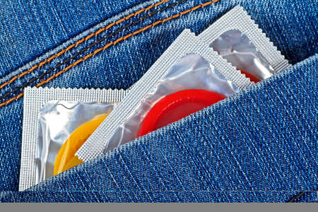 Three colored condoms in blue jeans pocket. Waiting for love and sex. の写真素材