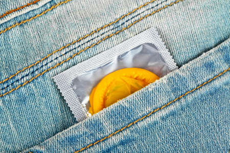 Yellow condom in a blue jeans pocketの写真素材